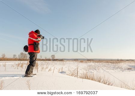 photographer takes winter landscape at dawn in the bitter cold.