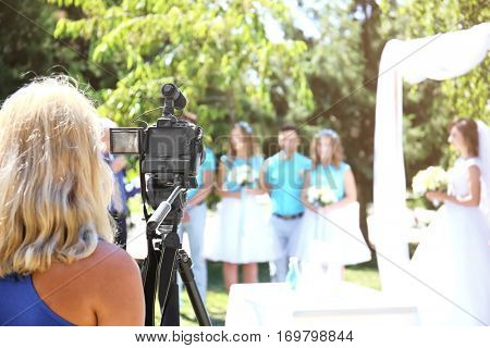 Camerawoman recording video and newlyweds on background
