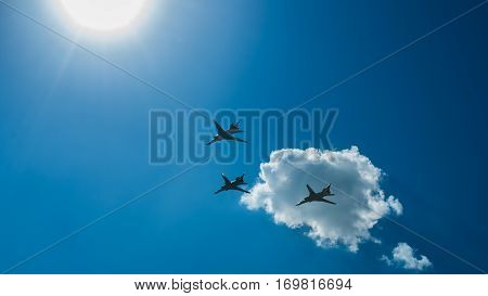 three aircraft fly over the city on a background of blue sky