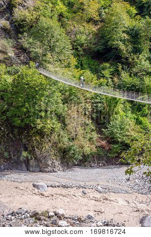 People Passing Over The Hanging Monkey Bridge