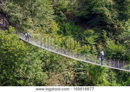 People Passing Over The Hanging Monkey Bridge