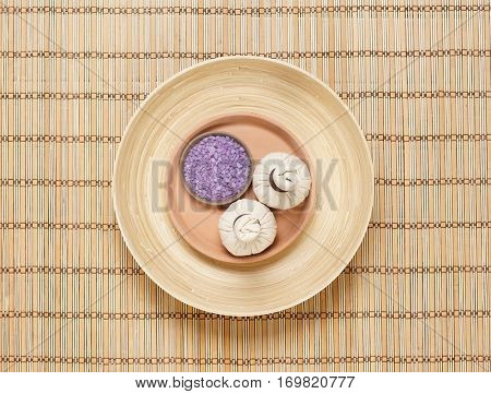 Massage bundle on a plate with bath salt over bamboo mat. Spa, health, treatment concept.