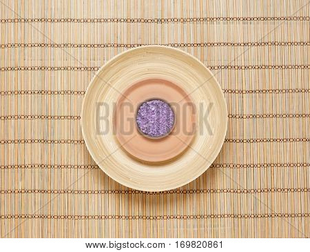 Plate with bath salt on bamboo mat. Health, treatment, spa concept.