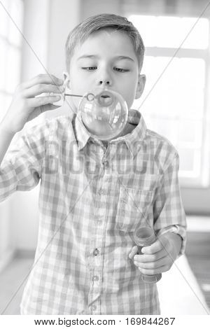 Cute boy playing with bubble wand at home