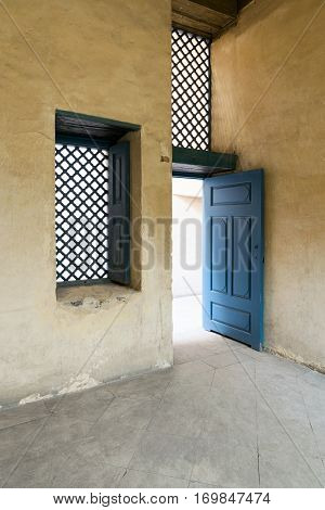 Blue vintage wooden window with interleaved wooden grid (mashrabiya) and blue wooden door with plaster yellow wall