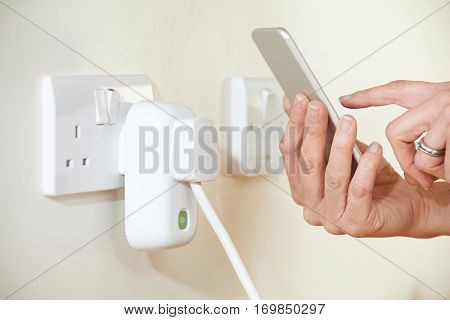 Woman Controlling Smart Plug Using App On Mobile Phone