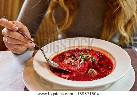 Red Ukranian Beet soup. Girl eating healthy at lunch in a restaurant