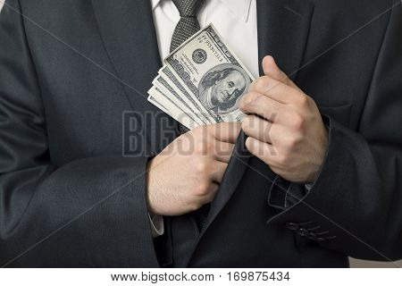 Detail of a man in a suit placing money in his jacket pocket. Selective focus