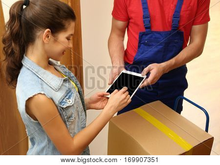 Young woman appending signature after receiving parcel from courier at home