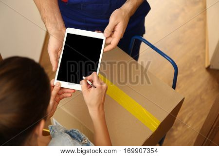 Young woman appending signature after receiving parcel from courier at home, closeup