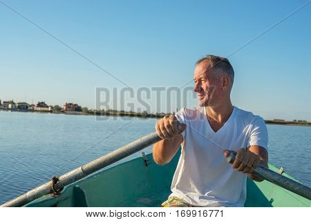 Smiling Man Is Rowing On A Small Boat In A Calm Sea