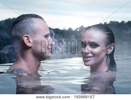 Hot spring geothermal spa on Iceland. Romantic couple in love relaxing in hot pool on Iceland. Young woman and man enjoying bathing relaxed in blue water lagoon Icelandic tourist attraction. Sunset.