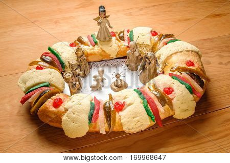 Epiphany Cake kings cake or Rosca de reyes with manger on wooden table