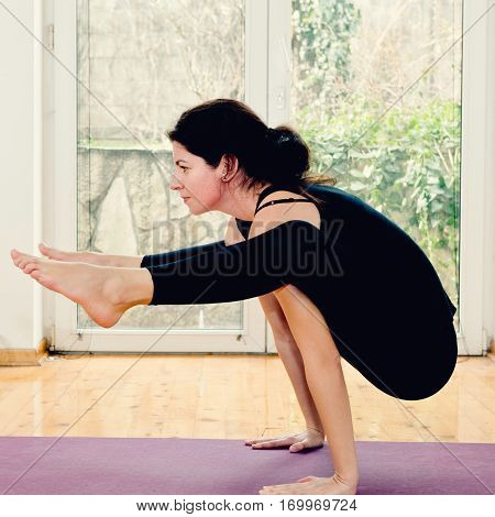 Woman Doing Yoga At Home - Tittibhasana Or Firefly Position