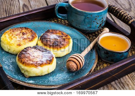 Pancakes with honey on vintage bowl on wooden tray. Studio Photo