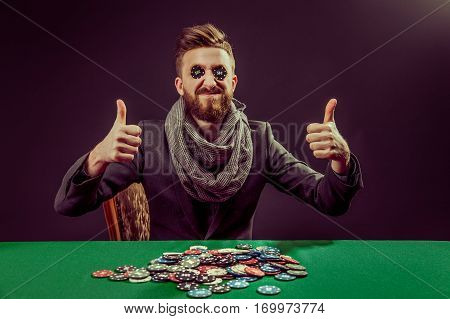 portrait of successful pocker player with thumbs up smiling while putting black chips in eyes