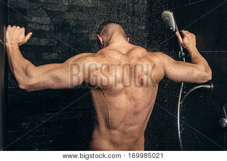 Muscular Fitness Bodybuilder Taking A Shower After Training. Close Up Details Of Back Muscles In Sho