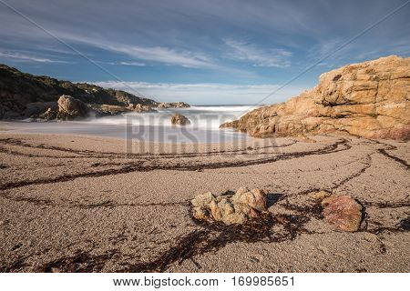 Waves Wash Onto A Small Sandy Cove Near Calvi In Corsica