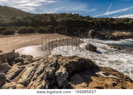 Waves Wash Onto A Small Sandy Cove Near Calvi In Corsica