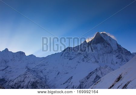 Before sunrise from Annapurna Base Camp (ABC) Trekking on the trail in the mountains. Sport girl with backpack travels in Himalayas. Nepal trek to ABC. Female traveler near Annapurna Base Camp. Snow a