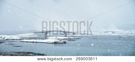 Fredvang bridges in heavy snowfall in winter with fishing ship. Lofoten islands, Norway