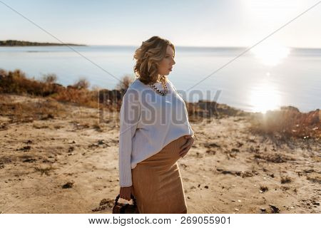 Pregnant Woman Walking Near The River During The Sunny Weather