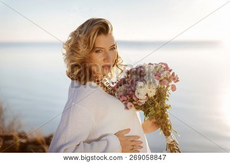 Happy Pregnant Woman Holding A Bunch Of Autumn Flowers