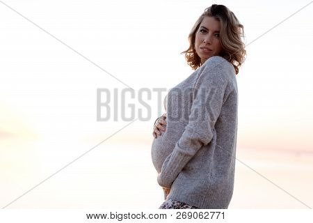 Pregnant Woman In A Sweater Holding Her Belly