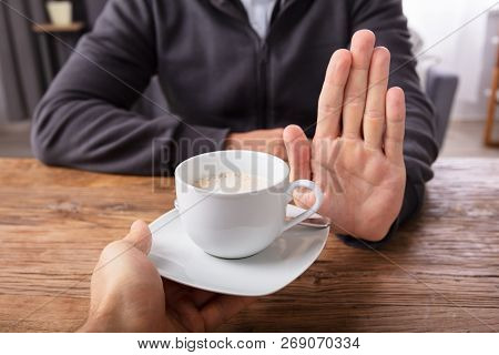 Man Refusing Cup Of Coffee Offered By Person