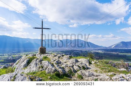 A Steel Cross On Top Hill Of The Mountain And Rays Of The Sun On A Blue Skies Background. Beautiful 