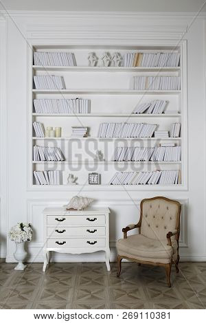 Interior Of Hite Roomwith Bookshelves, Armchair And A Chest Of Drawers.