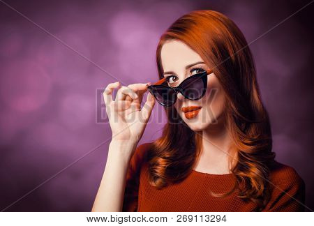 Beautiful Redhead Woman In Sunglasses On Viloet Background.