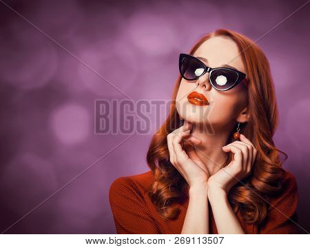Beautiful Redhead Woman In Sunglasses On Viloet Background.