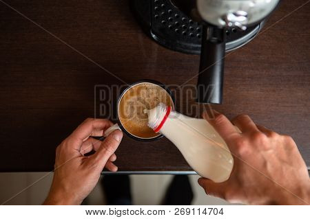 Photo Of Coffee Maker, Mans Hands Pouring Milk Into Mug Of Coffee In Kitchen