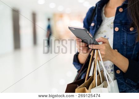 Asian Woman holding shopping bags and using smart phone 