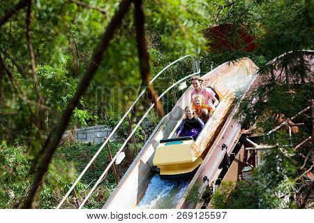 Family With Kids On Roller Coaster In Theme Park.
