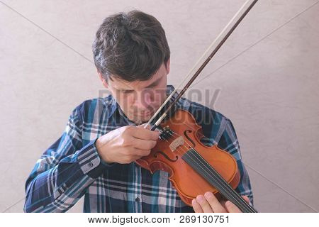Man Adjusts The Violin Twisting The Bolts And Playing It With A Bow.