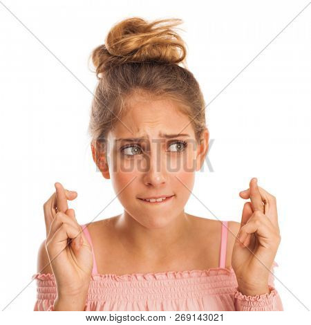 Body language and emotions concept. Glad dark haired beautiful satisfied girl beggs God to help her, keeps fingers crossed, wishes good luck, prays indoor isolated over gray studio background.