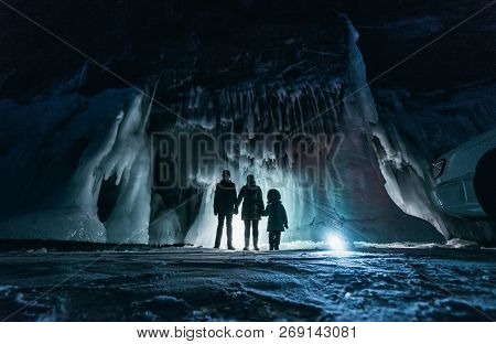 Surreal Landscape With People Exploring Mysterious Ice Grotto Cave. Outdoor Adventure. Family Explor