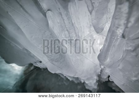 Winter Baikal. Olkhon Island. Ice Grotto. Thick Blue Ice And Icicles On The Coastal Rocks Of Olkhon 