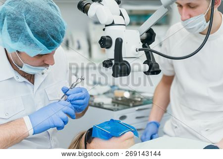 Doctor Used Microscope. Dentist Is Treating Patient In Modern Dental Office. Operation Is Carried Ou