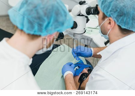 Doctor Used Microscope. Dentist Is Treating Patient In Modern Dental Office. Operation Is Carried Ou