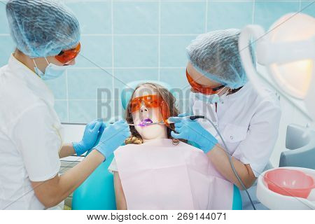 Girl Patient With Dentist And Assistant In A Dental Treatment