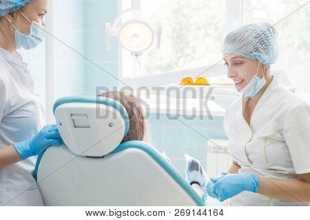 Girl Patient With Dentist And Assistant In A Dental Treatment
