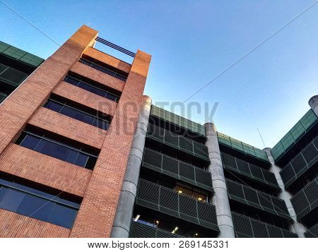 Low Angle View Of A Large Modern Building With Concrete Columns And Exterior Brick And Steel Facade.