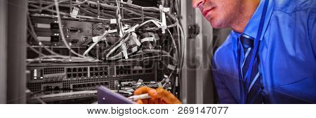 Technician maintaining record of rack mounted server on clipboard in server room