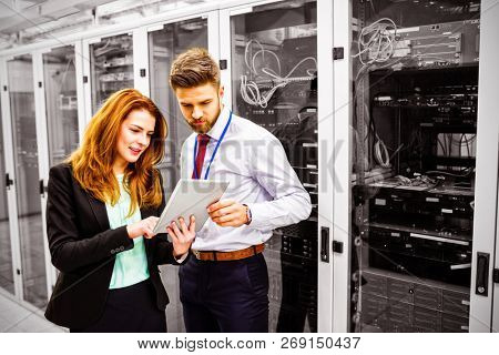 Technicians using digital tablet while analyzing server in server room