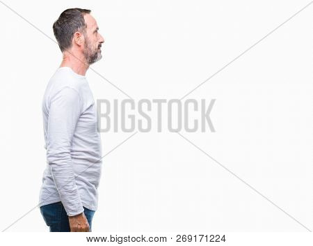 Middle age hoary senior man wearing white t-shirt over isolated background looking to side, relax profile pose with natural face with confident smile.
