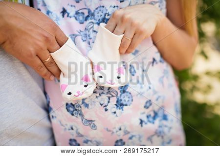Pregnant Woman With Husband Holding Child's Bootees With Kittens, Closeup