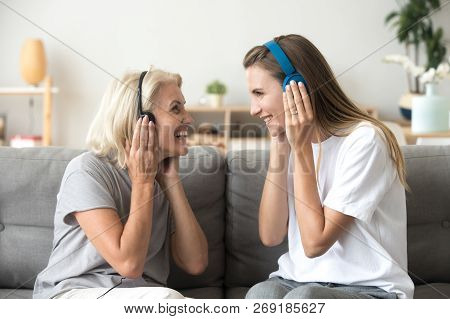 Happy Senior Mother And Adult Daughter Listening Music In Headph